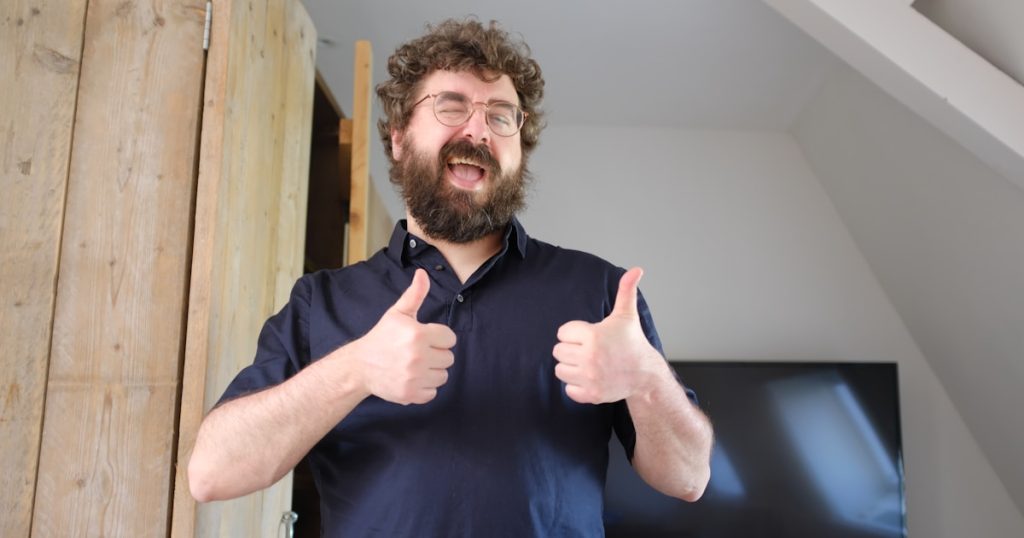 a man with a beard giving a thumbs up