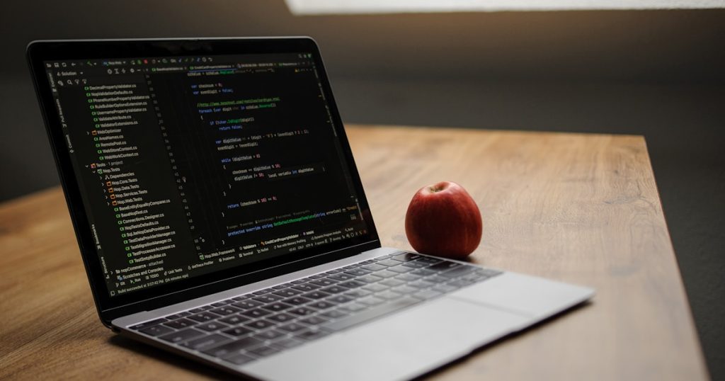 Laptop displaying code with an apple nearby